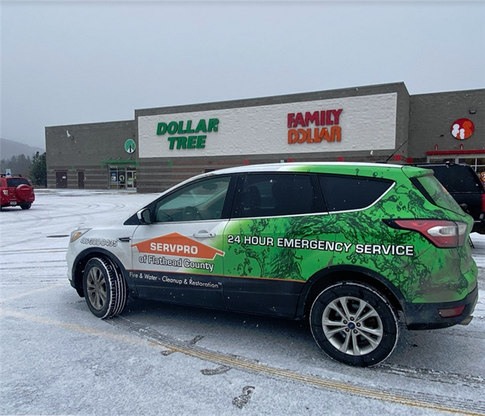 a SERVPRO car parked in front of stores