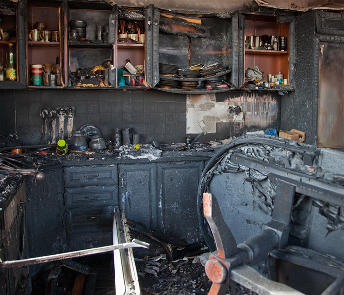 a fire damaged kitchen with soot covering the walls and debris covering the floors